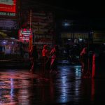 डार्क क्राइम ड्रामा के लिए रात में बारिश के बीच खड़े लोगों की प्रतीकात्मक तस्वीर